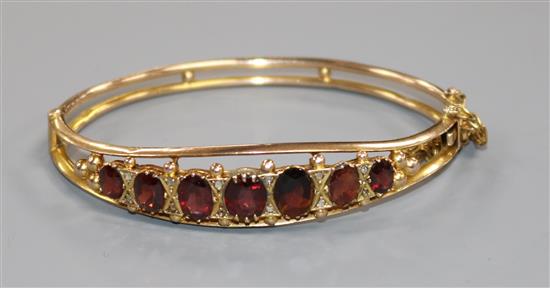 A 9ct gold and garnet set hinged bangle.